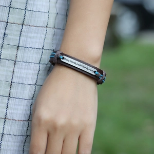 Detail of woven leather bracelet with engraved 'Where there's a will there's a way' metal plate