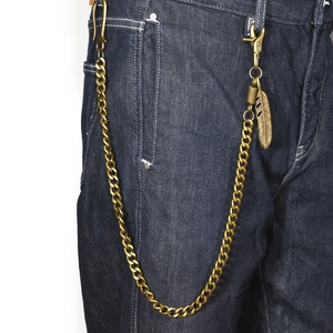 Retro brass wallet chain with feather pendant and heavy metal links on denim jeans