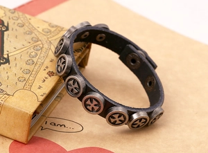 Detail shot of vintage punk black leather bracelet with round metal iron cross rivets