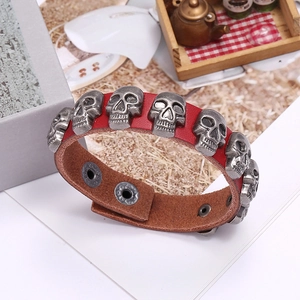 Detail view of red leather bracelet with silver skull charms and snap button closure