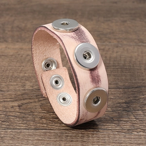 Retro light pink leather bracelet with three metal snap buttons on wood background