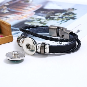 Detail of a black leather braided bracelet with metal beads and snap button closure
