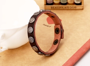 Close-up of a dark brown leather punk bracelet featuring vintage silver star metal studs