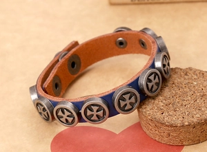 Detail of blue leather punk bracelet featuring silver maltese cross studs and snap button