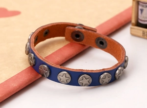 Detail of blue leather punk bracelet featuring matte silver star rivets and snap buttons