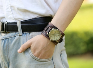 Macro shot of punk brown leather wide band strap and vintage brass quartz watch