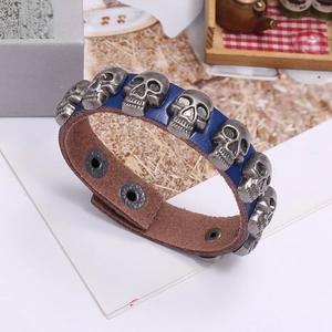 Detail of blue leather bracelet featuring vintage silver skull studs and metal snap closure