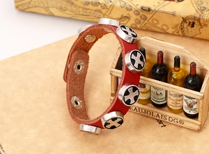 Close-up of red punk leather bracelet with silver cross studs and adjustable snap buttons