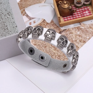 Detail of white leather punk bracelet featuring vintage silver skull charms and snaps