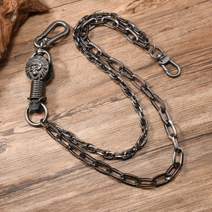 Retro double-layered pants chain with skull charm and metal lobster clasps on wood background