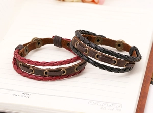 Detail of vintage braided leather bracelets in black and red with bronze metal eyelets
