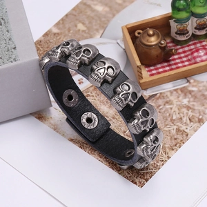 Detailed view of punk leather bracelet featuring silver metal skull studs and snap buttons