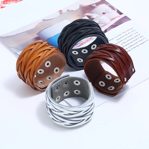 Dettaglio di bracciali in pelle intrecciata multistrato con bottoni a pressione in metallo