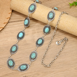 Bohemian silver chain belt with oval turquoise stones on a natural wooden background