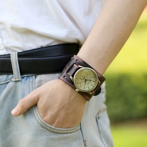Retro punk wide brown leather cuff watch with bronze dial on male wrist outdoors