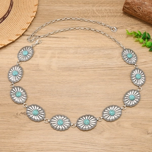 Detail of vintage silver metal waist chain with carved sunflower plaques and turquoise stones