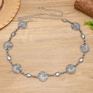 Detail of silver bohemian metal chain belt with ornate round links on a wooden background