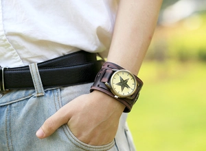 Macro detail of punk style wide leather wristband watch with a bronze star dial