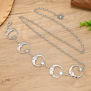 Silver waist chain belt with moon and sun charms on a rustic wooden background