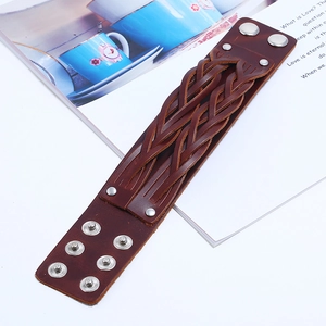 Dettaglio del bracciale largo in pelle intrecciata marrone con bottoni in metallo