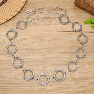 Detail of silver hollow circle waist chain with vintage metal patterns on wooden background