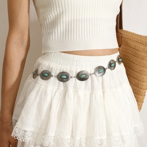 Detail of silver bohemian waist chain with turquoise stones on white lace dress