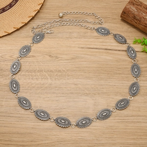 Macro detail of antique silver metal waist chain with ethnic embossed patterns
