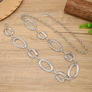 Minimalist silver metal chain belt with hollow oval links and adjustable clasp on wood background