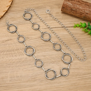 Minimalist geometric circular metal waist chain belt with silver finish on wood background