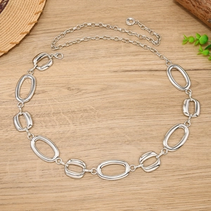 Close-up of polished silver metal waist chain with hollow oval rings on wooden background