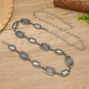 Vintage silver metal chain belt with embossed textures on a rustic wooden background