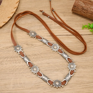 Detail of bohemian brown faux leather belt with vintage sunburst silver metal buckles