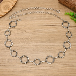 Macro detail of silver geometric waist chain with intertwined rings on wood surface