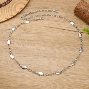 Detail view of silver metal chain belt with polished oval discs on a wooden background