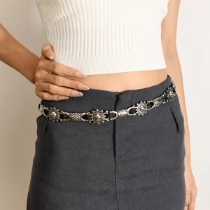 Close-up of bohemian silver sun-patterned metal belt paired with grey skirt