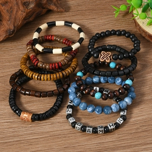 Détail de bracelets multicouches en perles de bois avec breloques lettres et accents