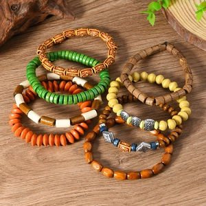 Close-up of bohemian wood bead bracelets set on a natural wooden background with green leaves