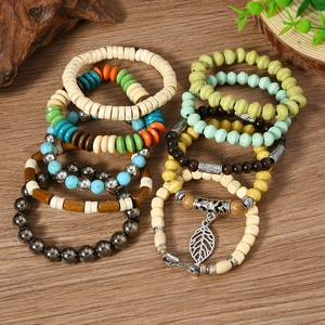 Detail of 10-piece bohemian beaded bracelets with wood beads and leaf pendant on wood table