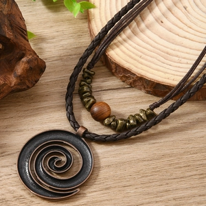Detail of bohemian long necklace with spiral pendant, wood beads on wood surface