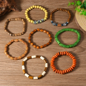 Flat lay of eight colorful handmade wooden beaded bracelets with ethnic bohemian textures