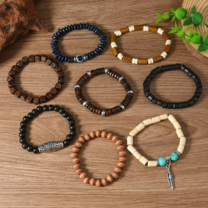 Detail of bohemian wood bead bracelet set with retro feather pendant on wooden background