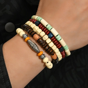 Detail of layered bohemian beaded bracelets with tribal wood and alloy charms on wrist