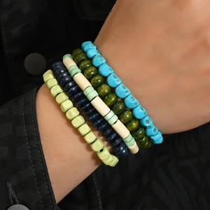 Close-up of stacked bohemian handmade beaded bracelets with colorful skull charm designs