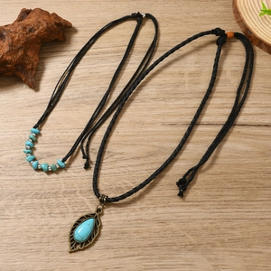 Detail view of bohemian turquoise leaf pendant necklaces on a natural wood background