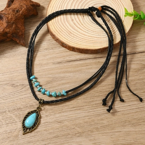 Bohemian double-layer necklace with turquoise leaf pendant on a rustic wooden surface