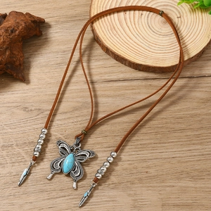 Détail du collier papillon bohème avec incrustation de turquoise et plumes argentées