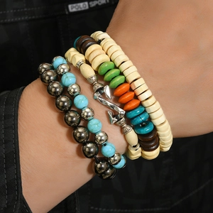 Detail of bohemian multilayer beaded bracelet set featuring wooden beads and silver anchor charm