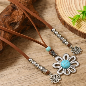 Vintage bohemian leather necklace with turquoise daisy pendant on natural wood backdrop