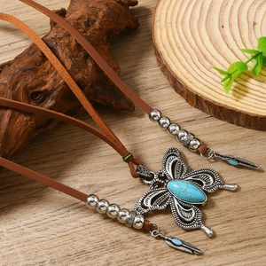 Collier bohème avec pendentif papillon en turquoise et cordon en cuir marron sur bois