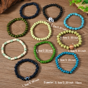 Set of 10 bohemian beaded bracelets with skulls and evil eye charms on wood background